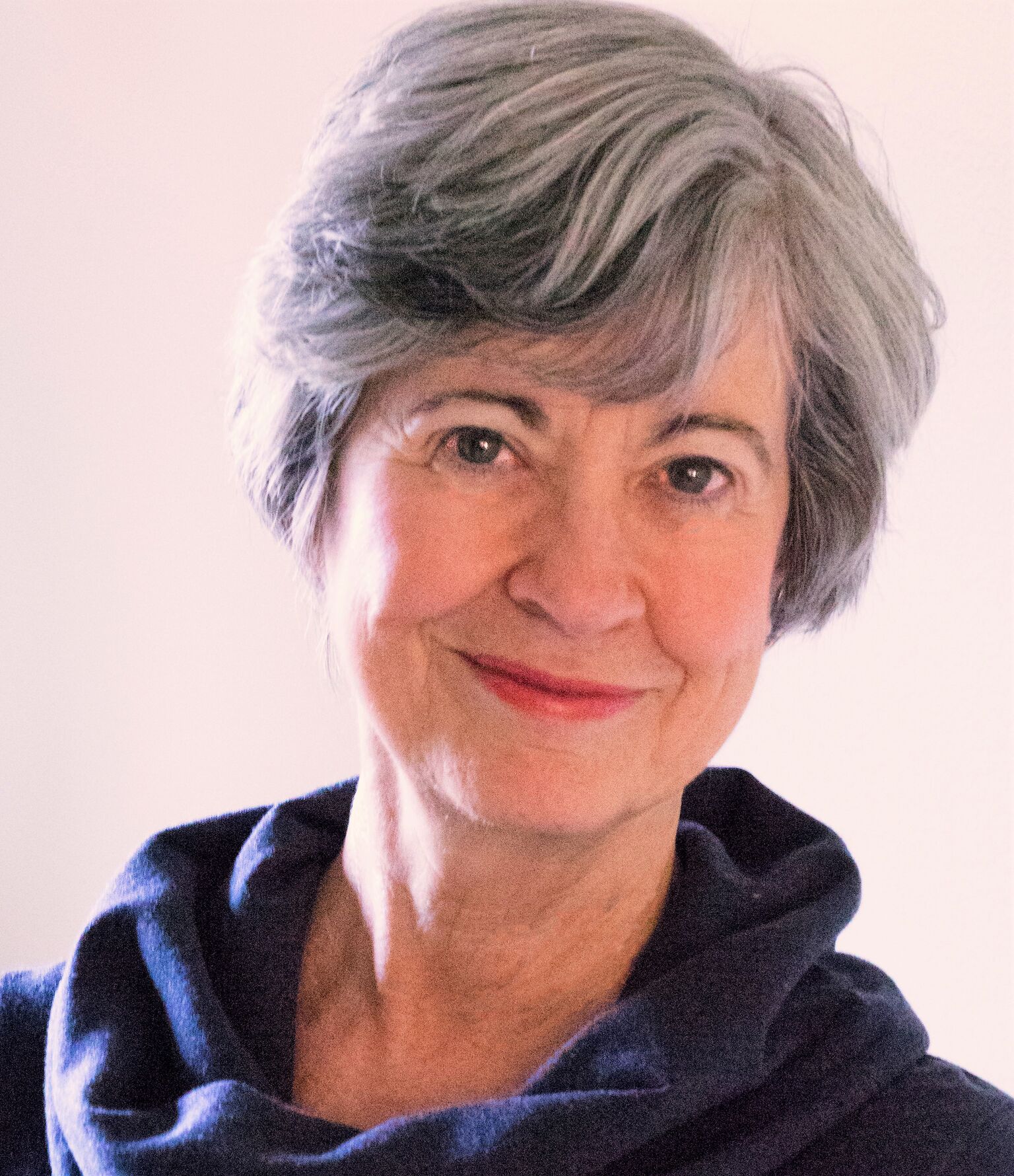 Smiling elderly woman with short gray hair and a blue scarf.