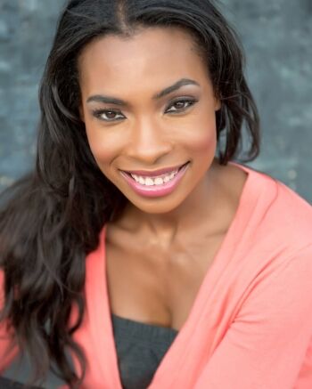 Smiling woman with long dark hair wearing a coral top.