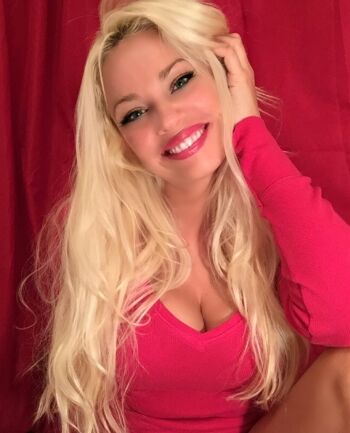 Smiling woman with long blonde hair and red top against a red background.