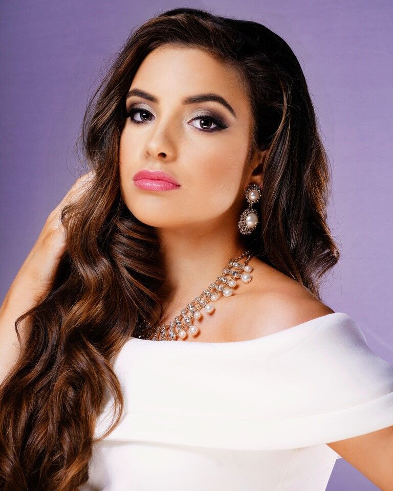 Elegant woman with long wavy hair and glamorous makeup.